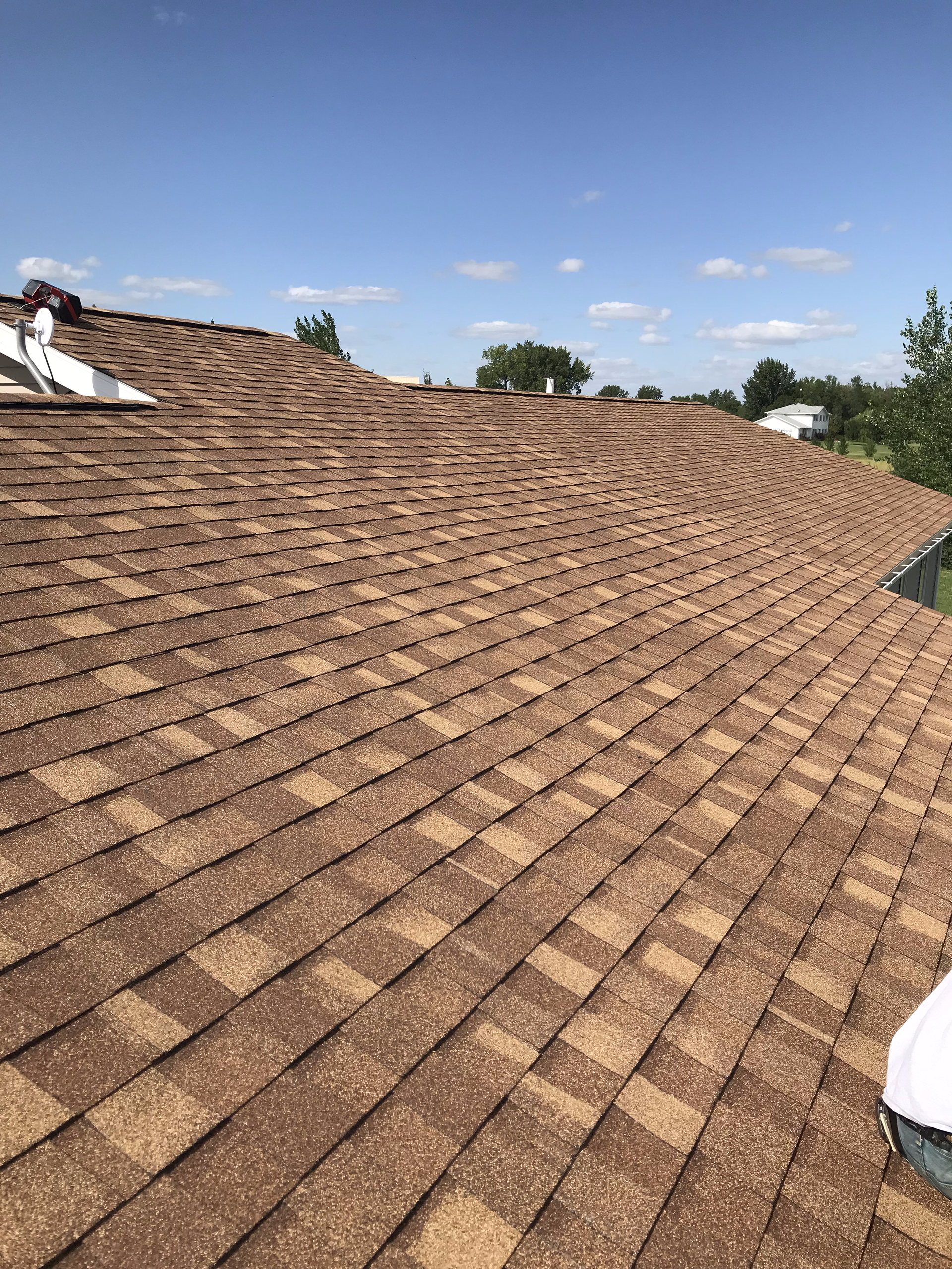 A close up of a roof with a blue sky in the background. Residential Roofing Replacement