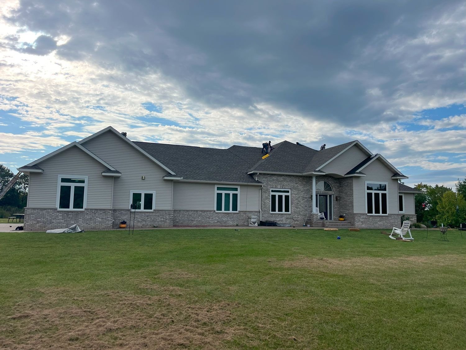 A large house is sitting on top of a lush green field.