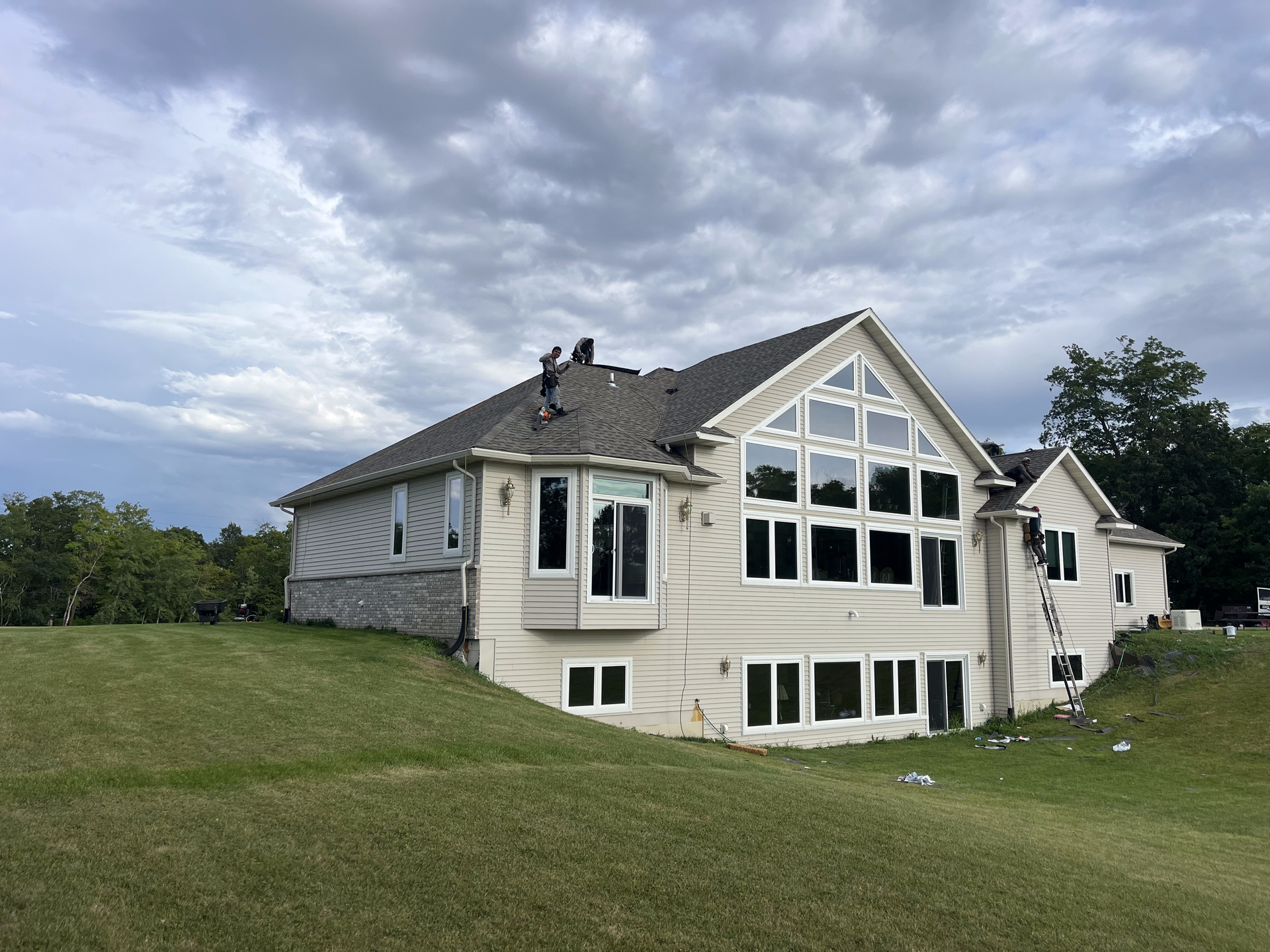 A large house with a lot of windows is sitting on top of a grassy hill.