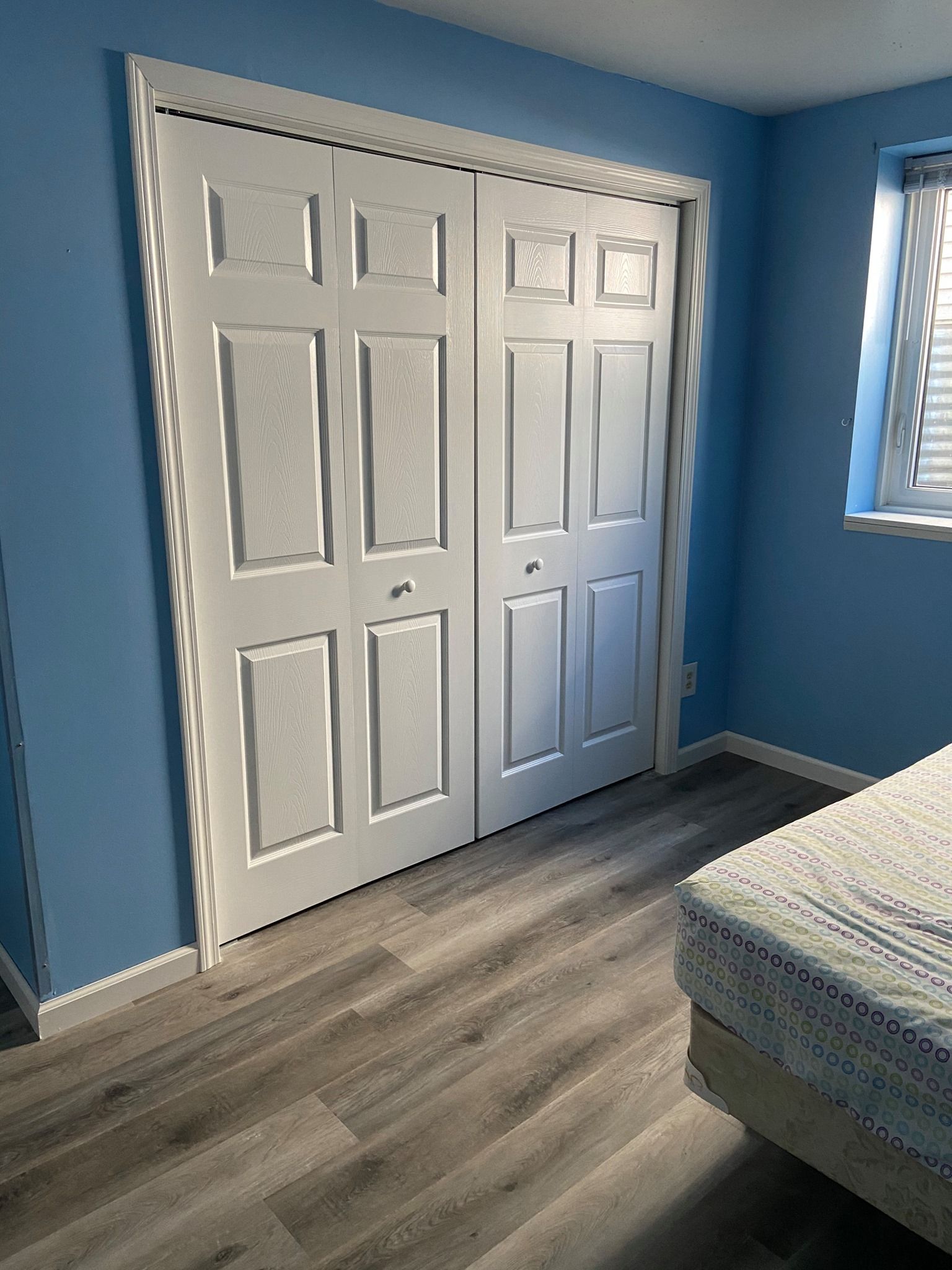 A bedroom with blue walls and white doors and a bed.