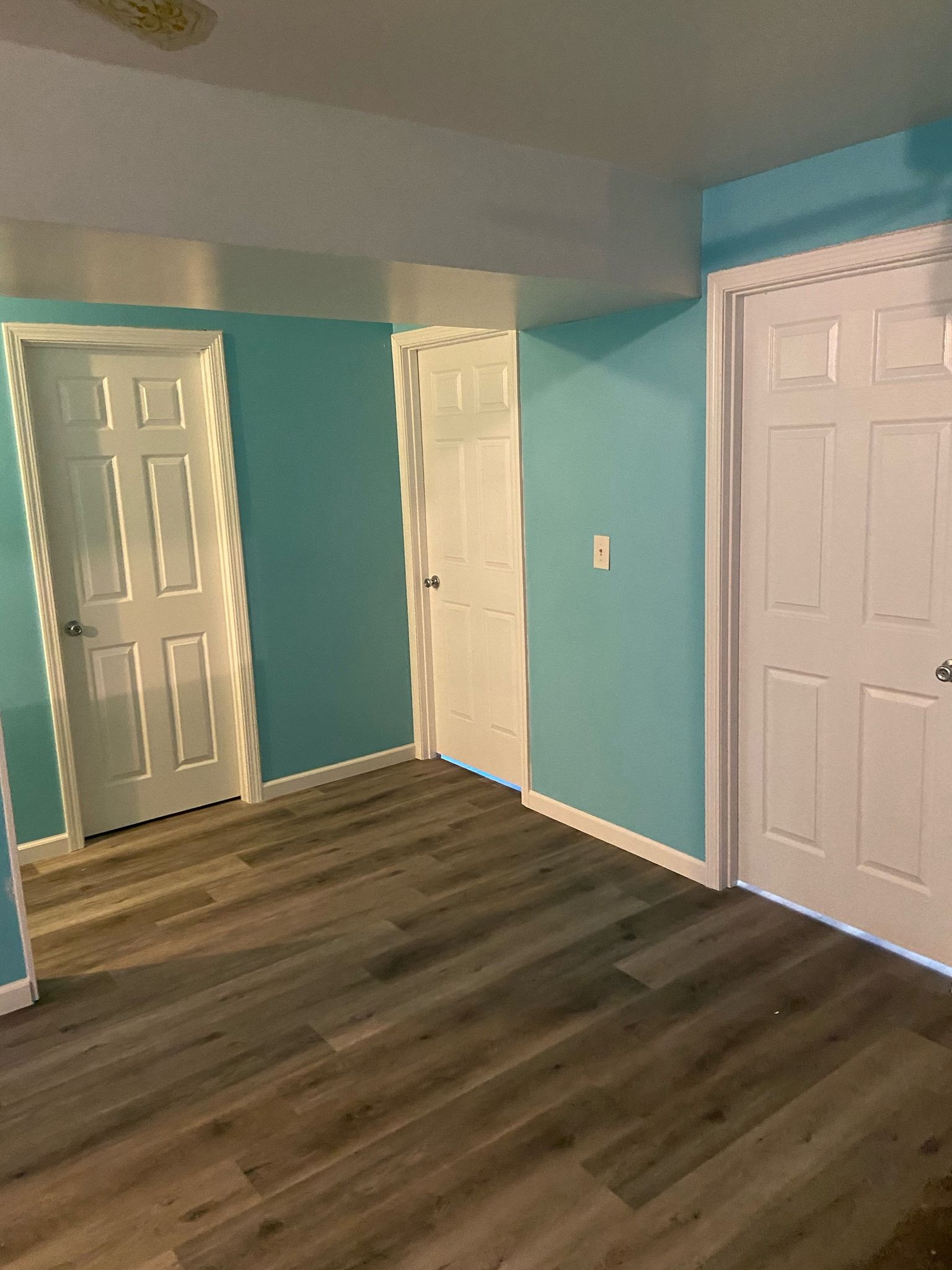An empty room with blue walls and white doors.