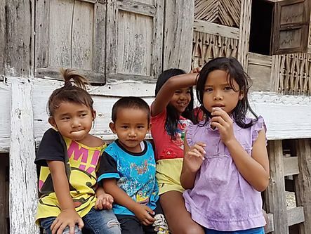 A group of children are posing for a picture in front of a wooden building.