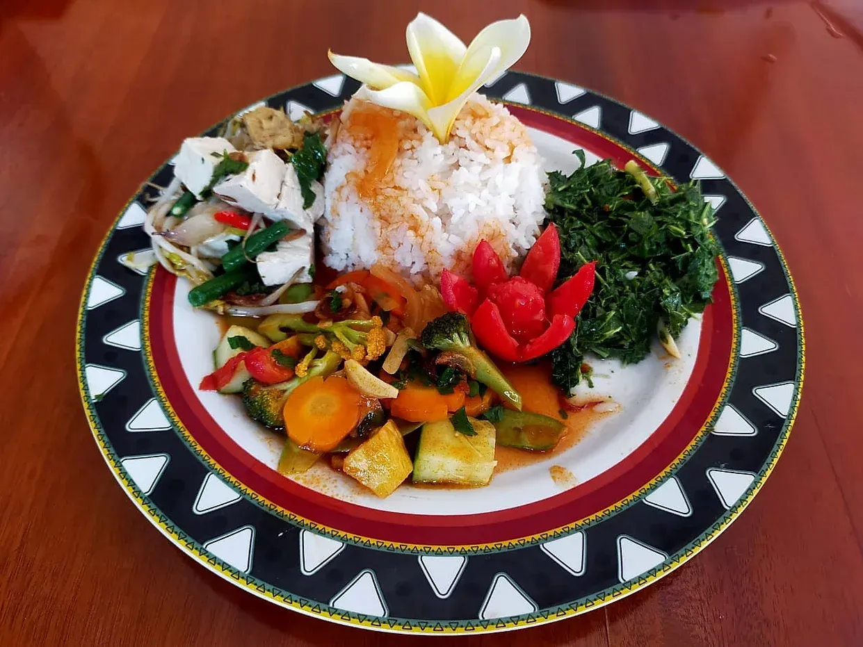 A plate of food with rice and vegetables on a wooden table