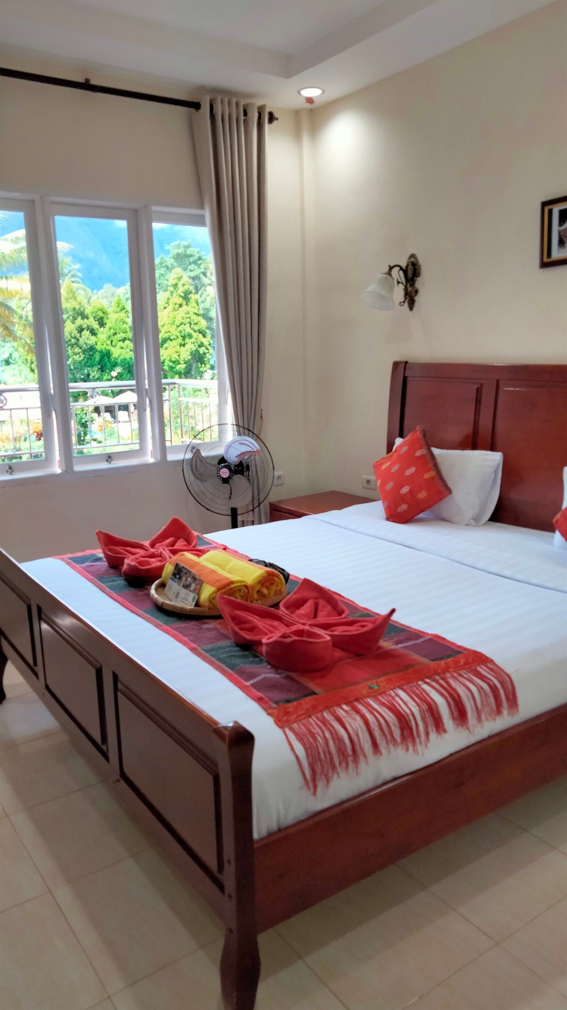 A hotel room with a king size bed and a fan.