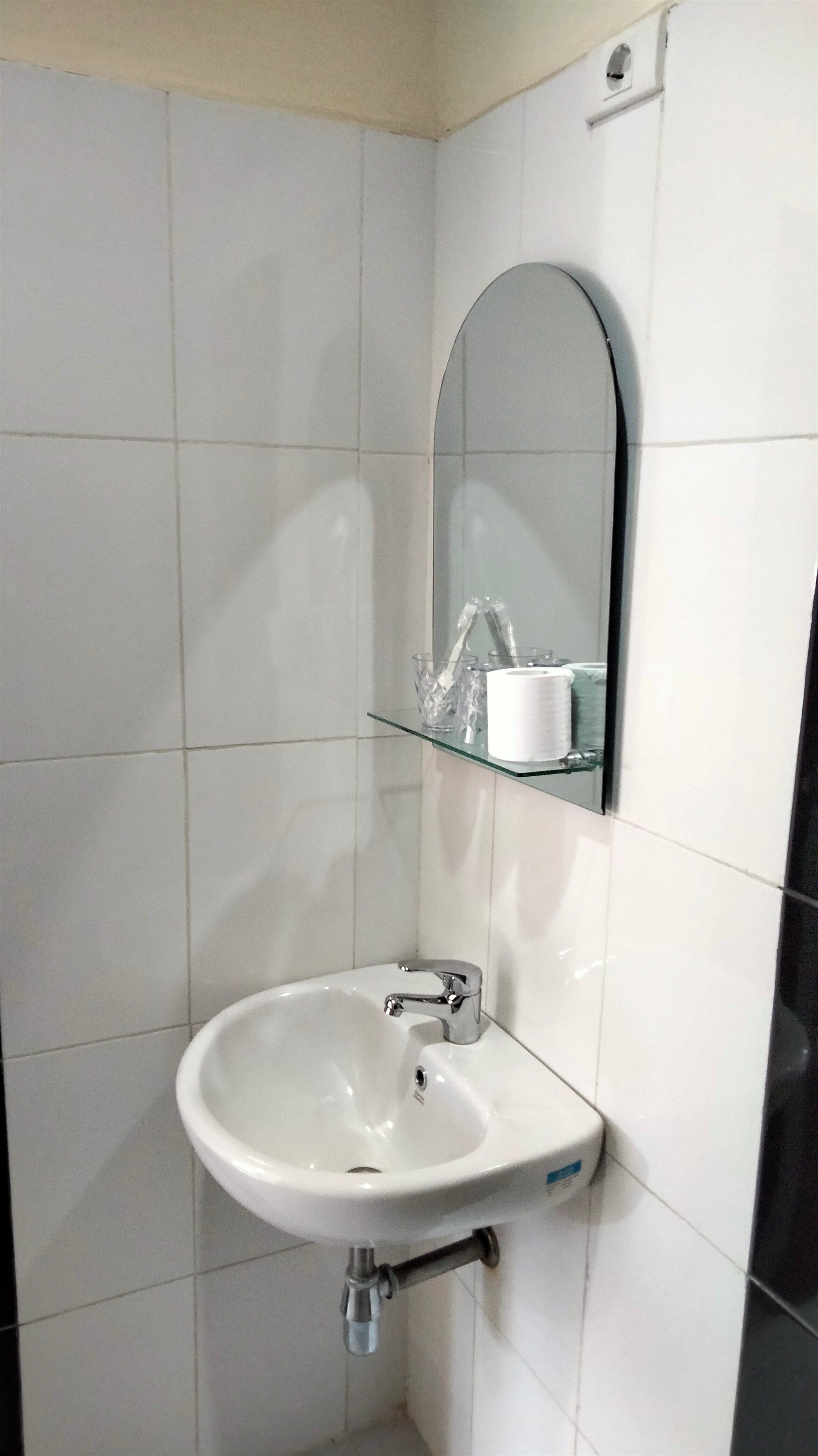 A bathroom with a sink , mirror and toilet paper.
