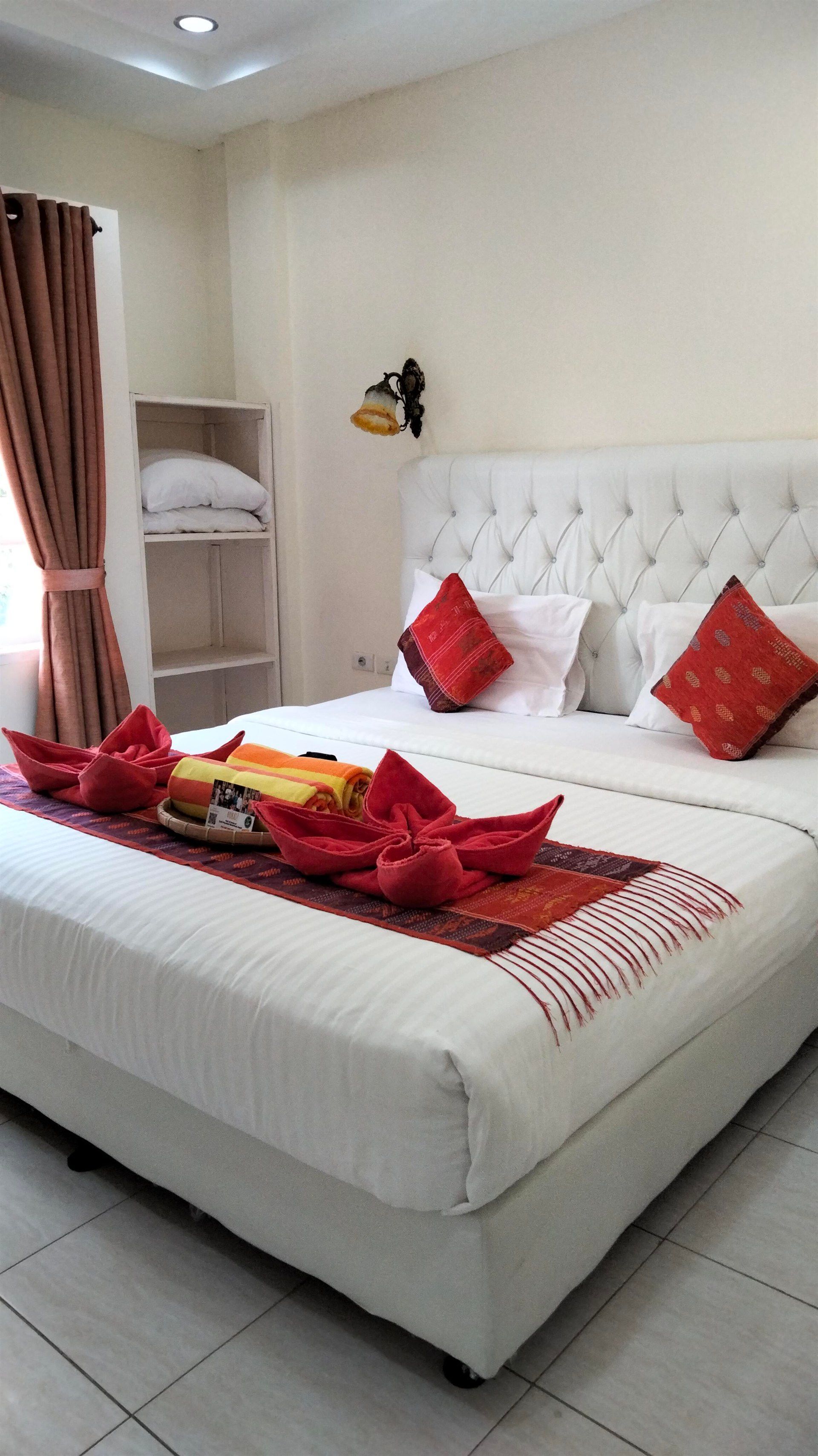 A hotel room with a large bed and red pillows.