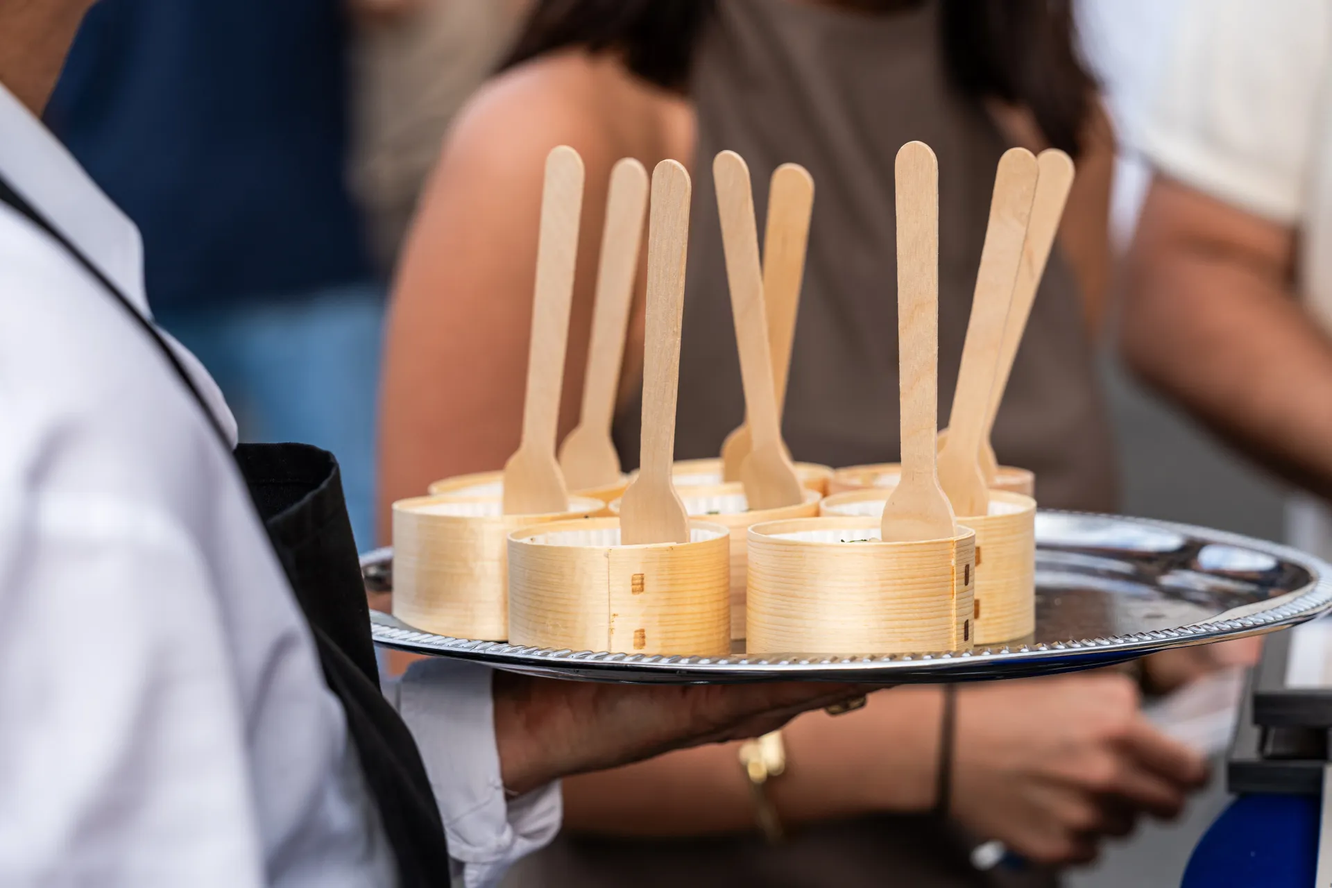 cocktail confidentiel service clé en main Serveur tenant un plateau d'amuse-gueules au fromage avec des fourchettes en bois.
