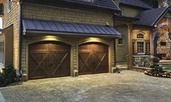 A large wooden garage door is in front of a large house.