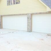 There are two garage doors on the side of a house.