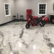 A red motorcycle is parked in a garage with a marble floor.