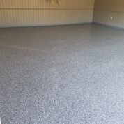 A garage with a gray floor and a white wall.