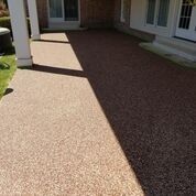 A concrete driveway in front of a house with a porch.