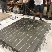 A group of men are standing around a brick floor.