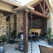 A patio with a table and chairs under a covered porch.