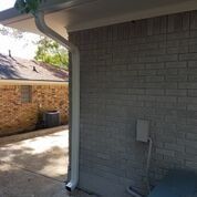 A brick house with a white gutter on the side of it.