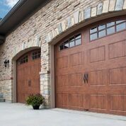 A couple of wooden garage doors on a brick building.