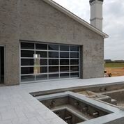 A house with a large garage door and a swimming pool in front of it.