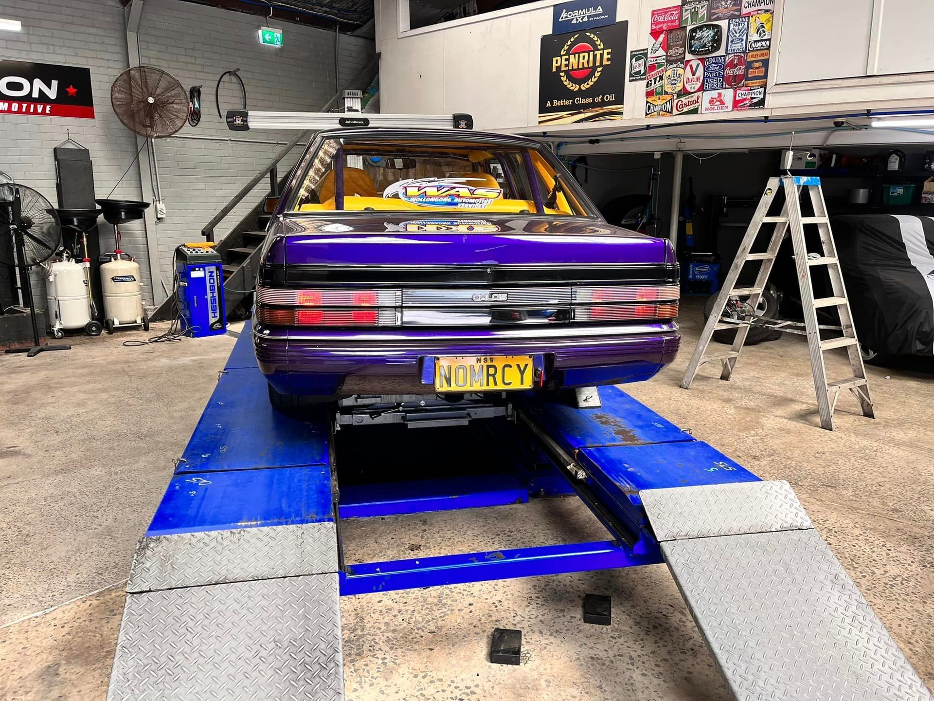 A Purple Car Is Sitting on A Blue Ramp in A Garage — Mechanic in Wollongong, NSW