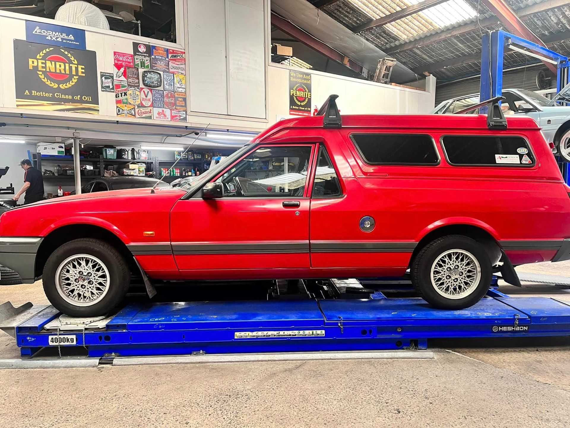 A Red Car Is Sitting on Top of A Blue Lift in A Garage — Mechanic in Wollongong, NSW