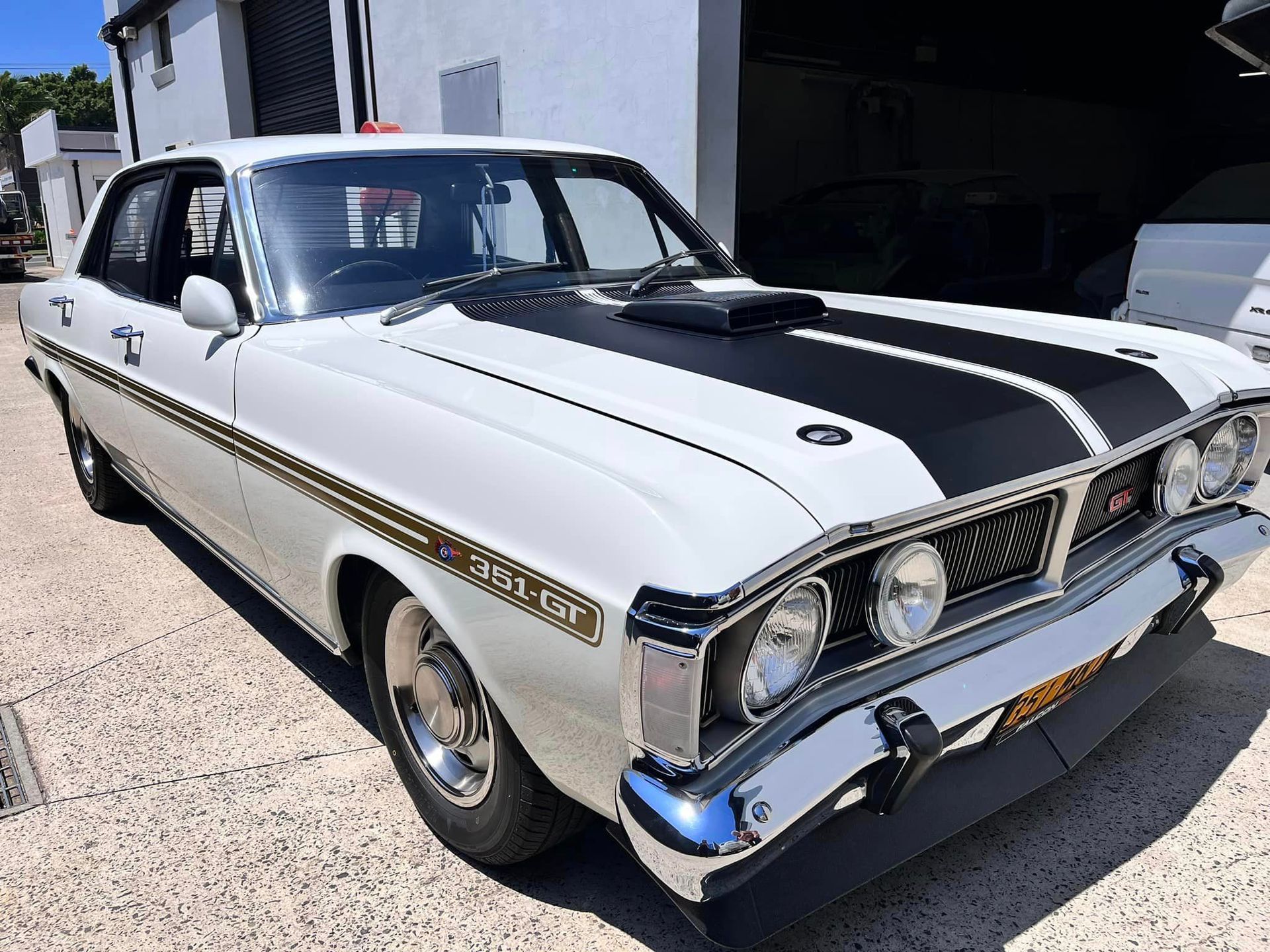 A White Car with Black Stripes on The Hood Is Parked in Front of A Garage — Mechanic in Wollongong, NSW