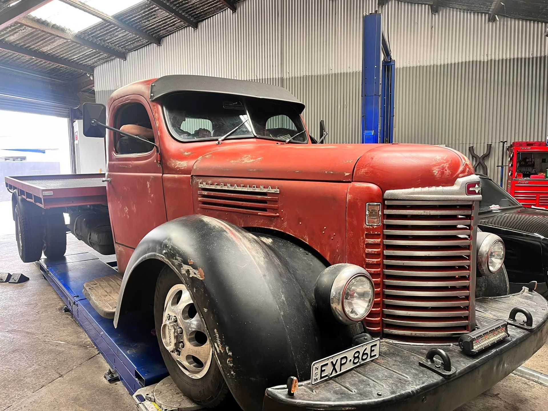 An Old Red Truck Is Parked in A Garage on A Lift — Mechanic in Wollongong, NSW