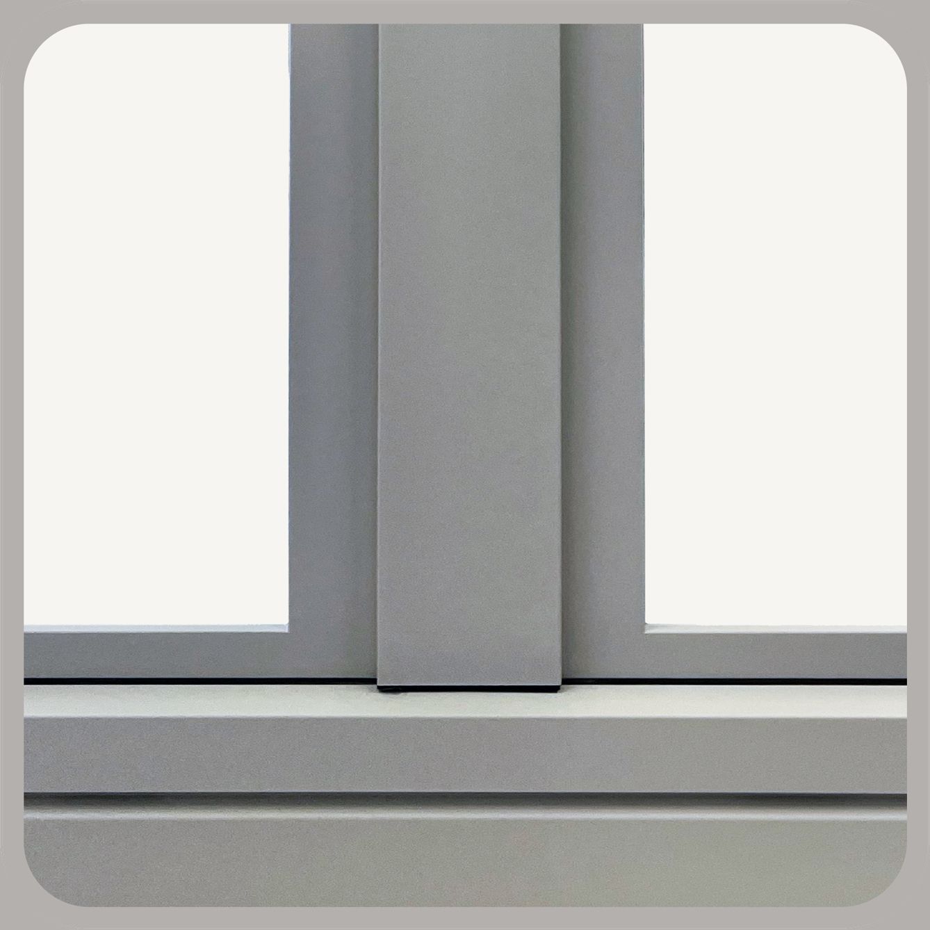 Primo piano di un telaio e davanzale di una finestra grigia con un montante verticale centrale che separa due pannelli di vetro bianco.