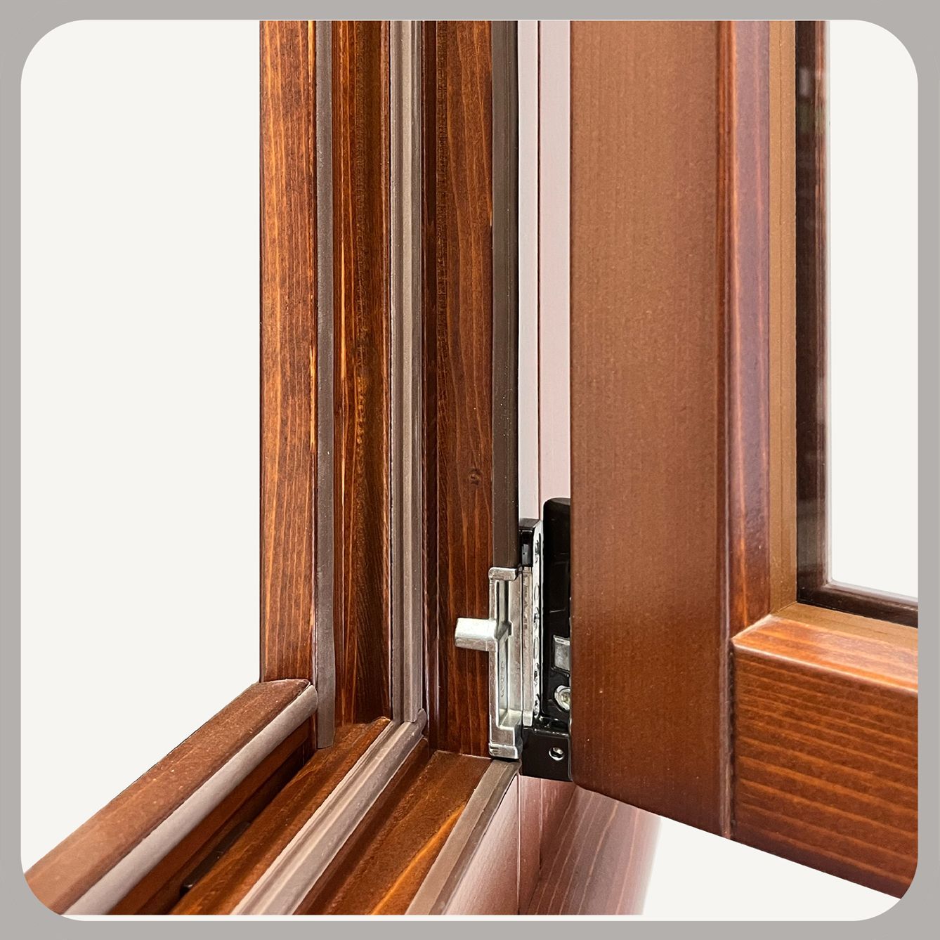 Vista ravvicinata del meccanismo di una cerniera metallica su una finestra con telaio in legno, che mostra i dettagli della ferramenta.