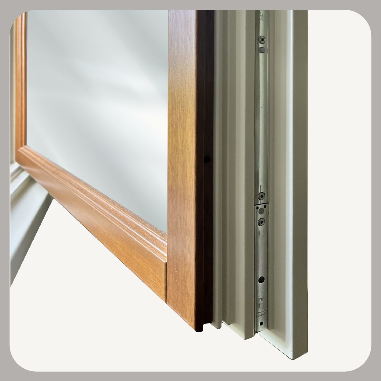 Vista ravvicinata del meccanismo di una cerniera metallica su una finestra con telaio in legno, che mostra i dettagli della ferramenta.