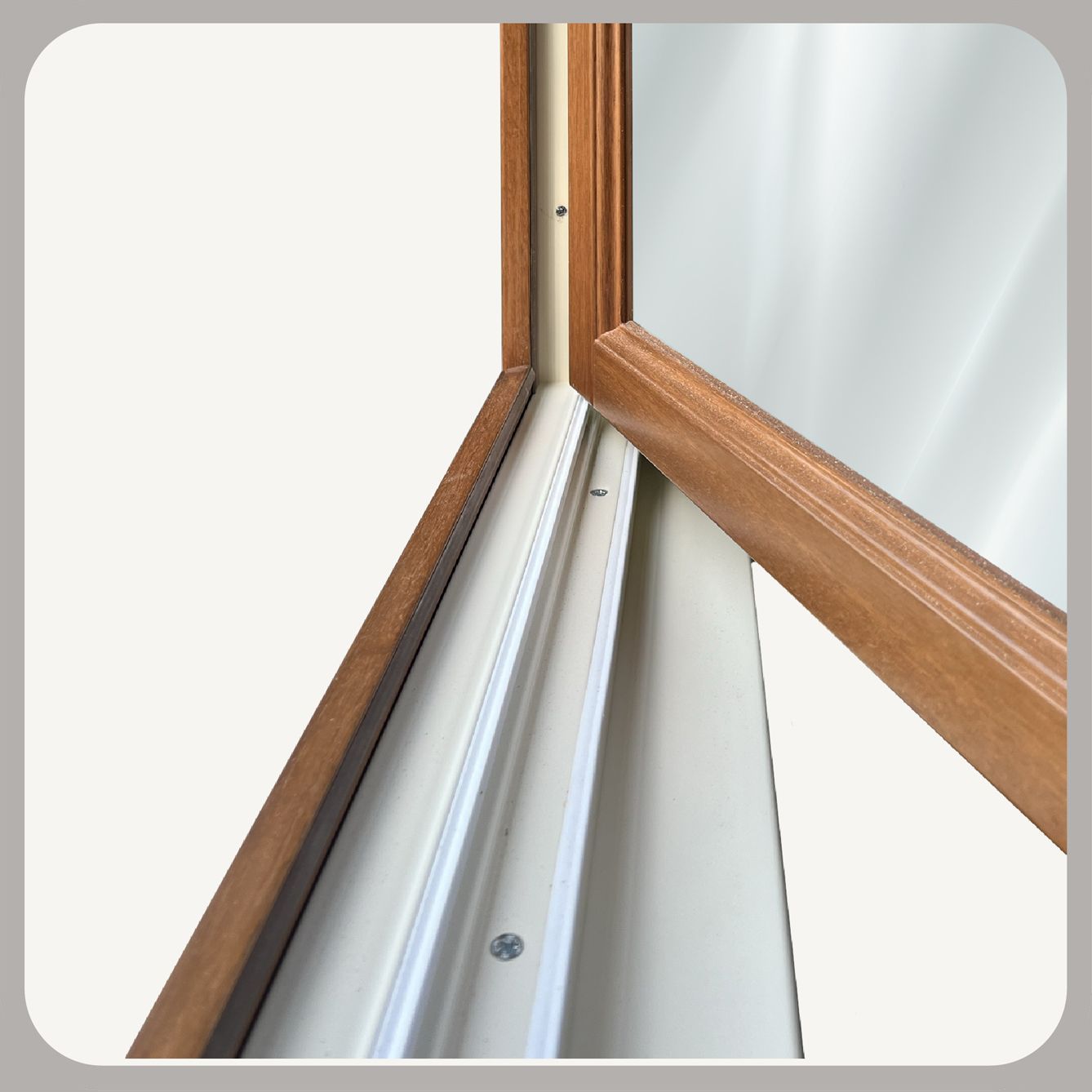 Vista ravvicinata degli incastri in legno tinto di un telaio di finestra, che mostra l'intersezione tra un montante verticale e un traverso.