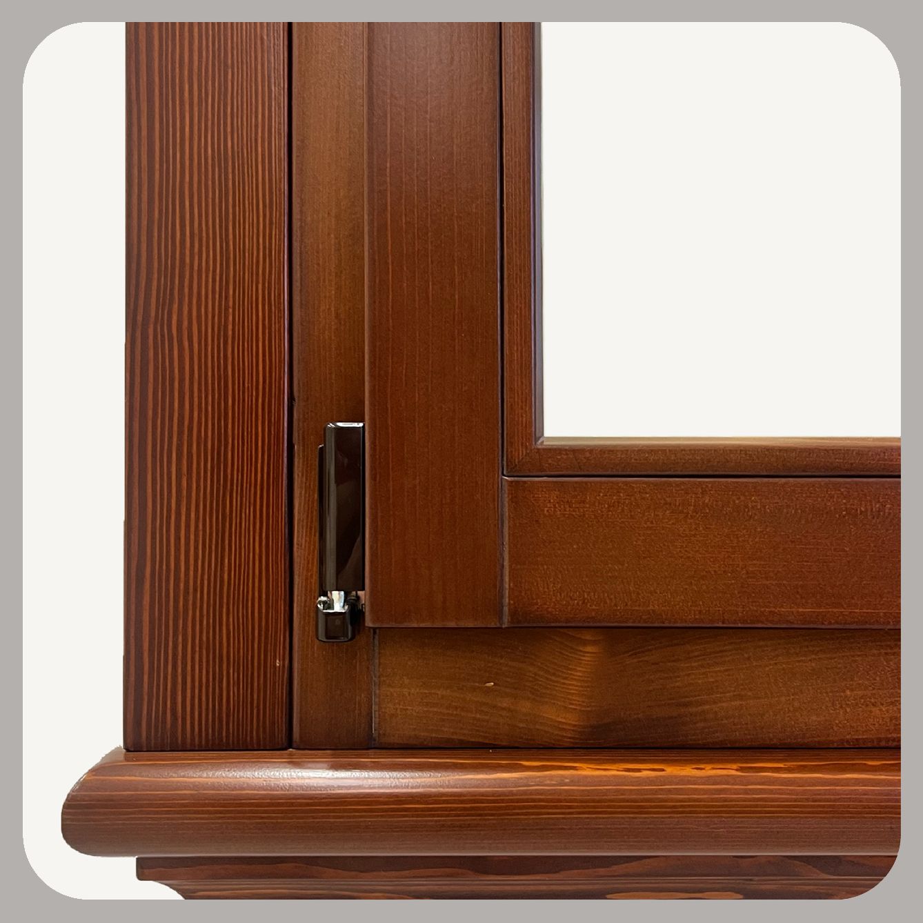Primo piano di un telaio di finestra in legno marrone con chiusura in metallo e venature del legno ben visibili.