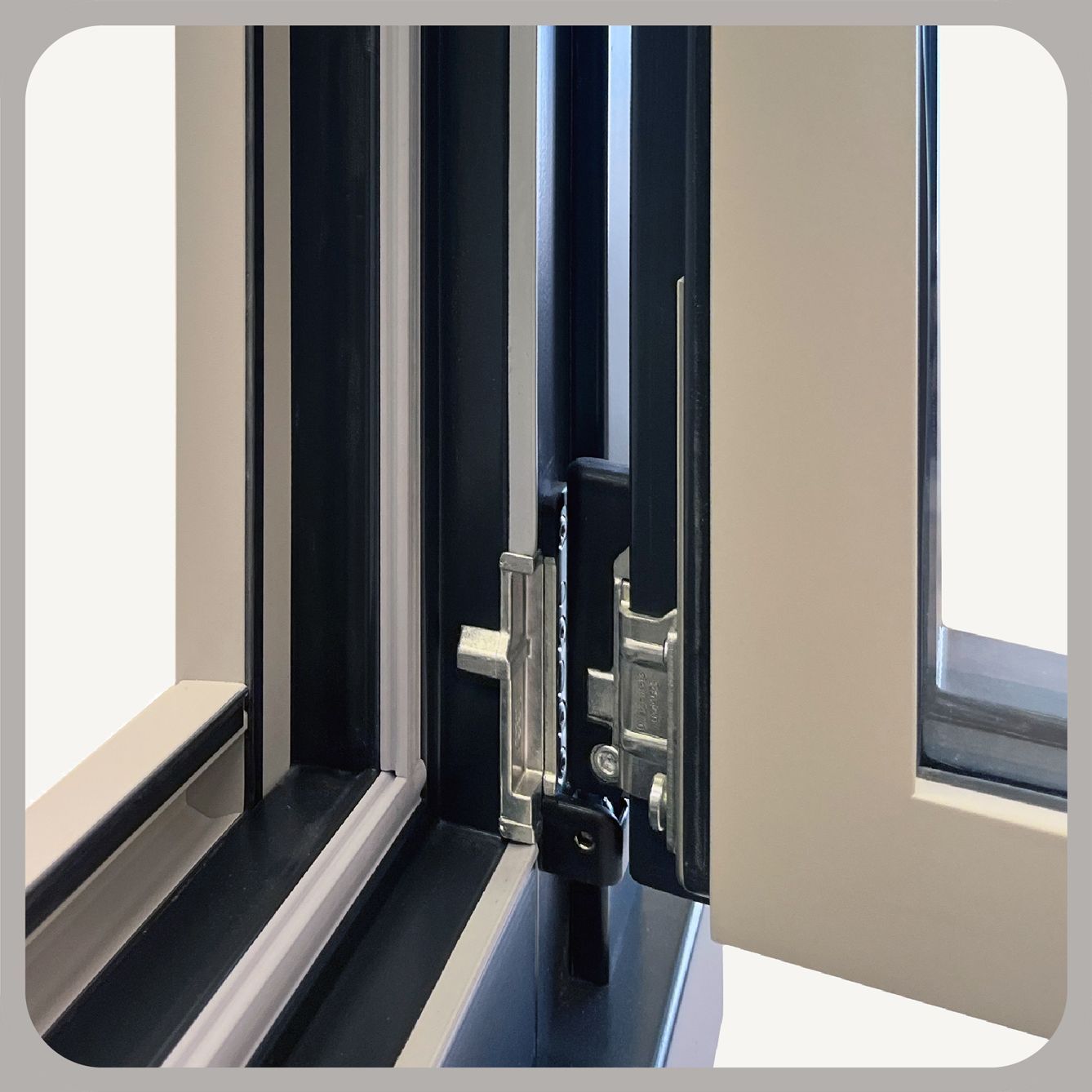 Primo piano di un moderno telaio per finestra con meccanismo di chiusura e cerniera in metallo, con finitura bianca e grigio scuro.