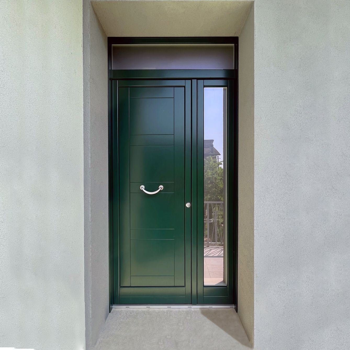 Una porta d'ingresso verde scuro con maniglia argentata e finestra laterale 