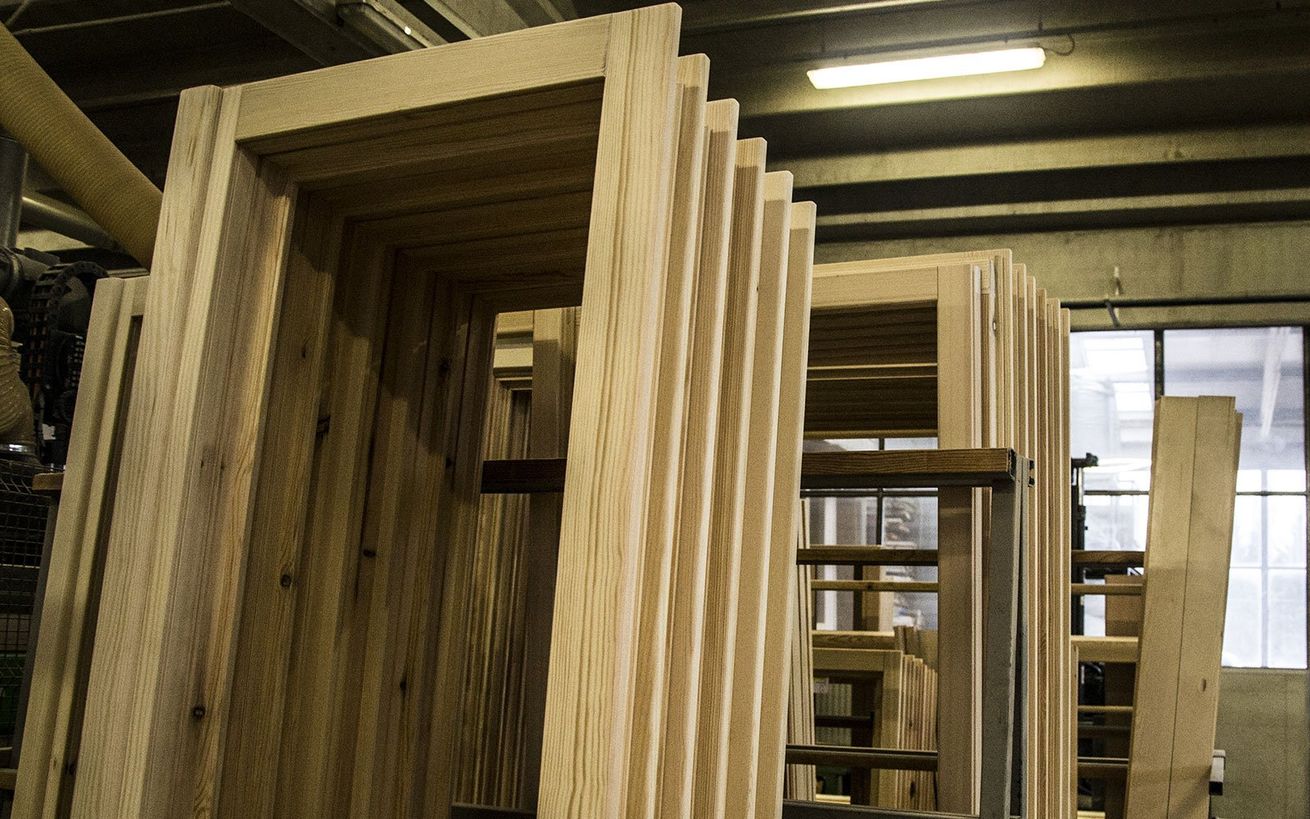 Telai di porte in legno impilati in un'officina di produzione.