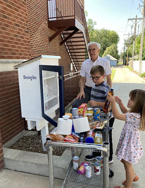 a small boy and small girl filling a grocery cart with items from blessing box at church