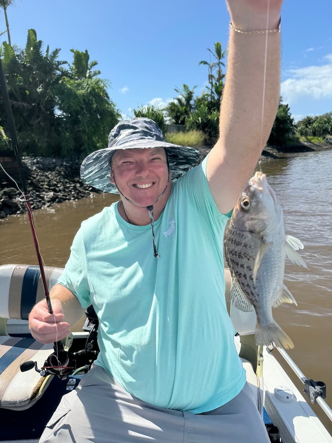 A Man is Sitting on a Boat Holding a Fish in His Hand — Mentally Hooked in Robina, QLD