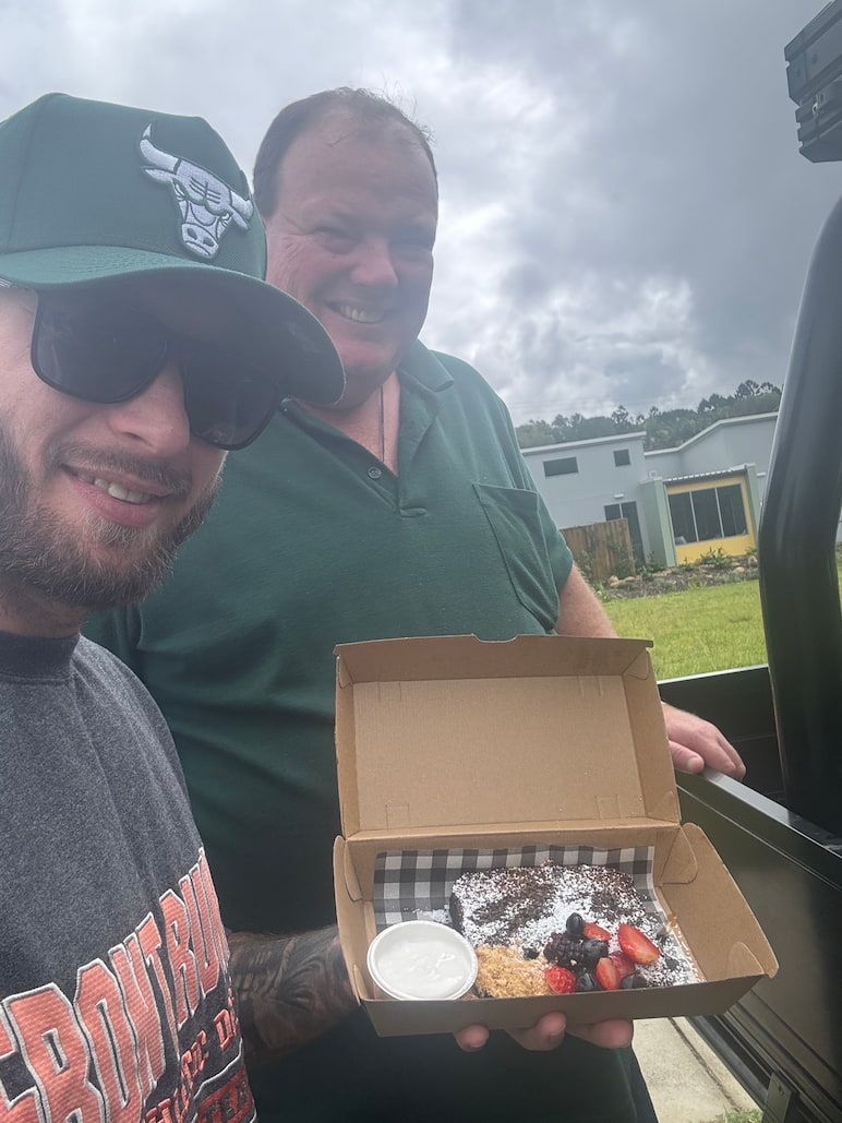 A Man Wearing a Chicago Bulls Hat is Holding a Box of Food — Mentally Hooked in Robina, QLD