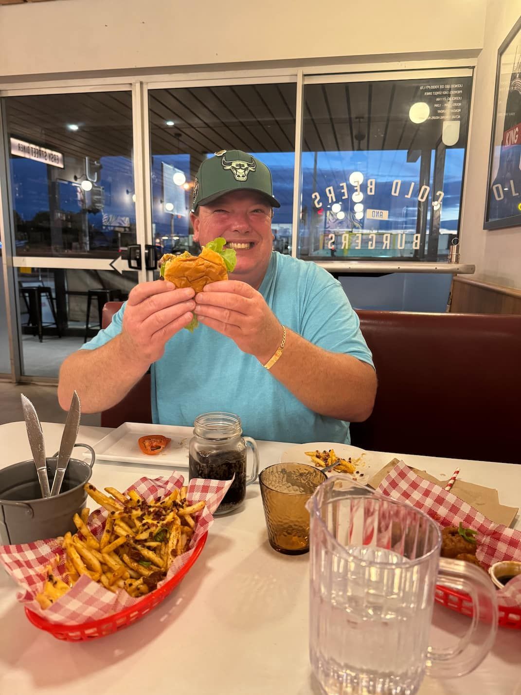A Man is Sitting at a Table Eating a Hamburger and French Fries — Mentally Hooked in Robina, QLD