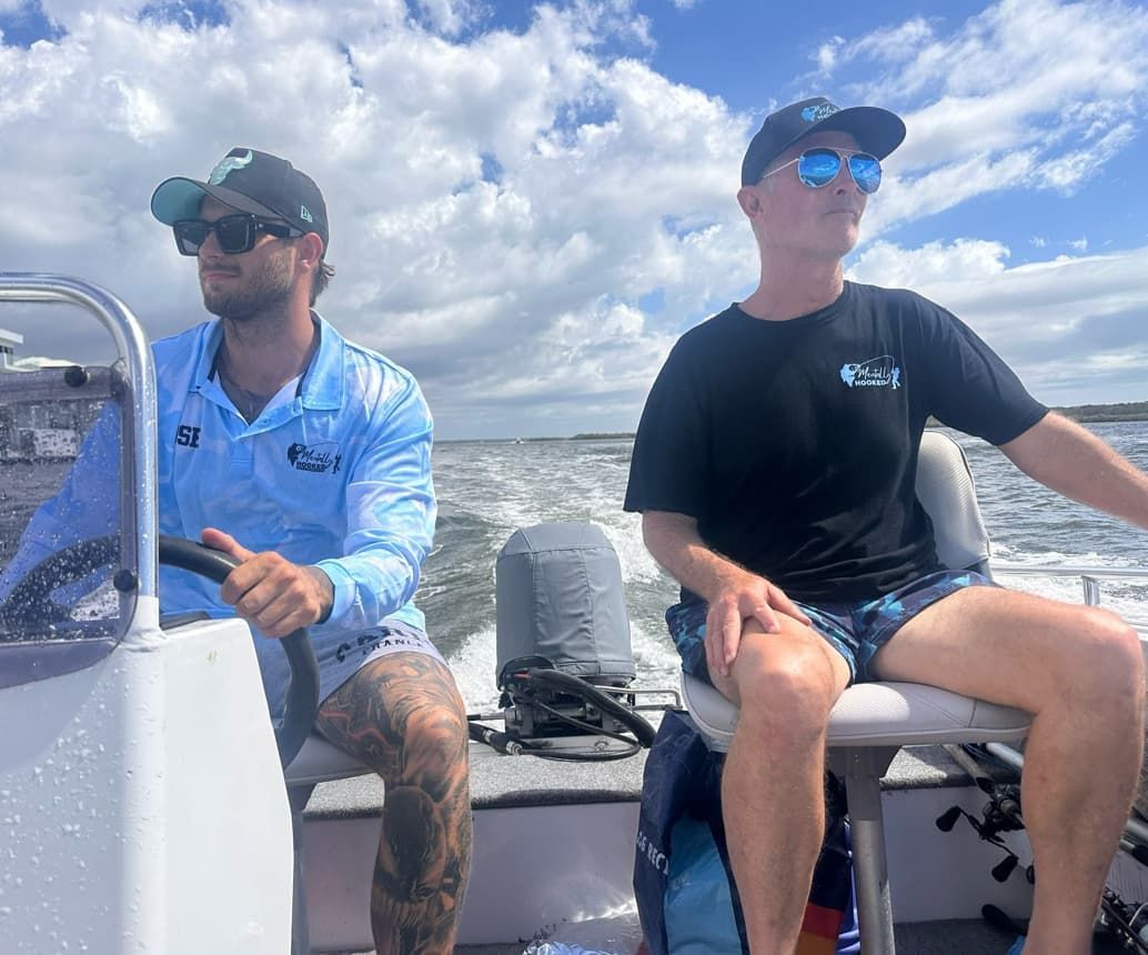 Two Men Are Sitting on a Boat in the Water — Mentally Hooked in Robina, QLD