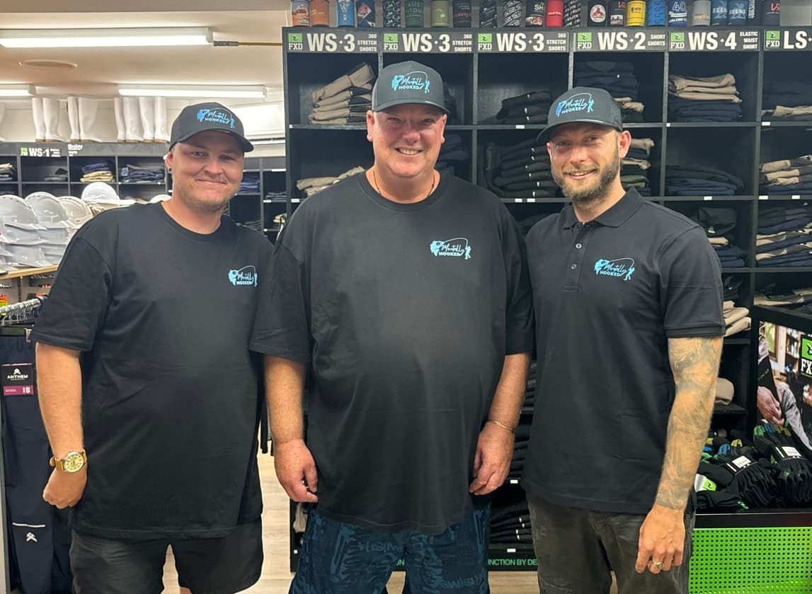 Three Men Wearing Black Shirts and Hats Are Standing — Mentally Hooked in Robina, QLD