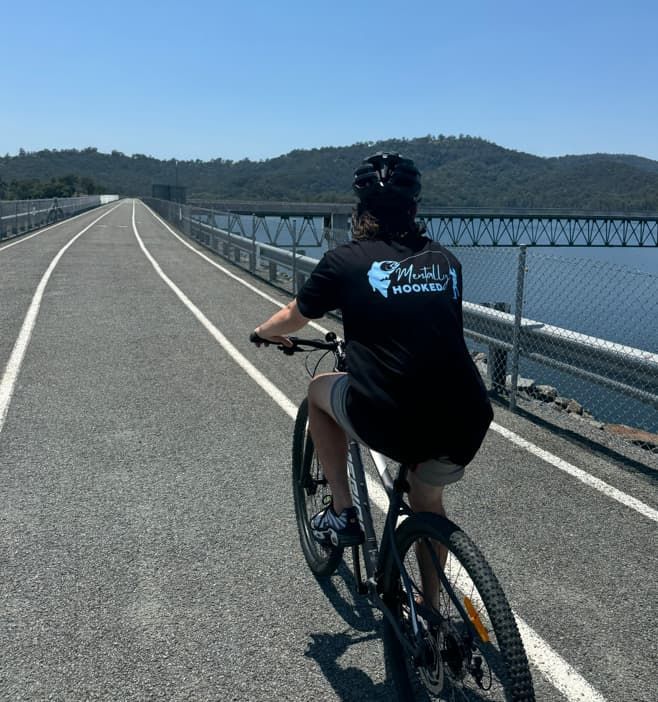 A Person Riding a Bike on a Road With a T-shirt That Says Mail on the Back — Mentally Hooked in Robina, QLD