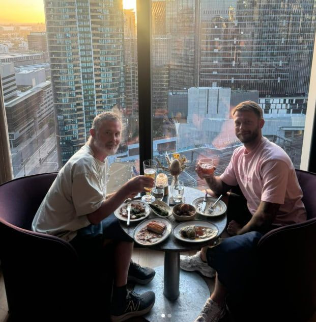 Two Men Are Sitting at a Table With Plates of Food and Drinks — Mentally Hooked in Robina, QLD