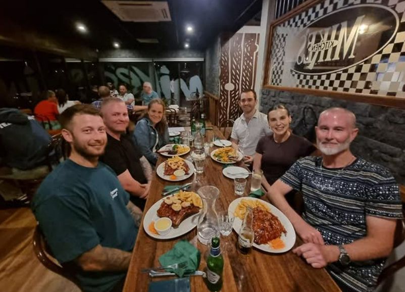 A Group of People Are Sitting at a Table With Plates of Food — Mentally Hooked in Robina, QLD