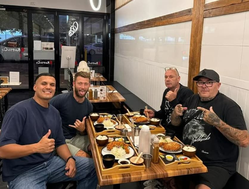 A Group of Men Are Sitting at a Table in a Restaurant Eating Food — Mentally Hooked in Robina, QLD