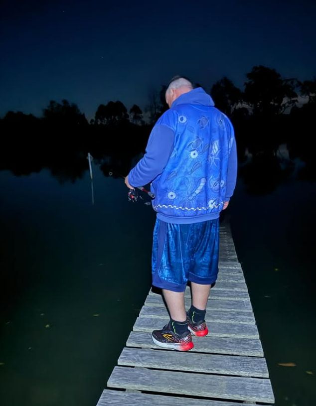 A Man in a Blue Jacket is Standing on a Dock Overlooking a Body of Water — Mentally Hooked in Robina, QLD