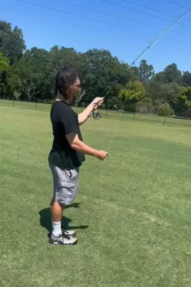 Man fly fishing on a green field under a clear blue sky — Mentally Hooked in Brisbane, QLD