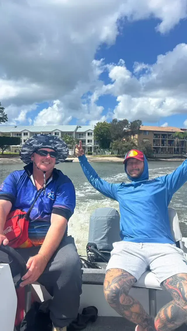 Two people on a boat on a sunny day. One raises arms, the other wears a hat — Mentally Hooked in Brisbane, QLD