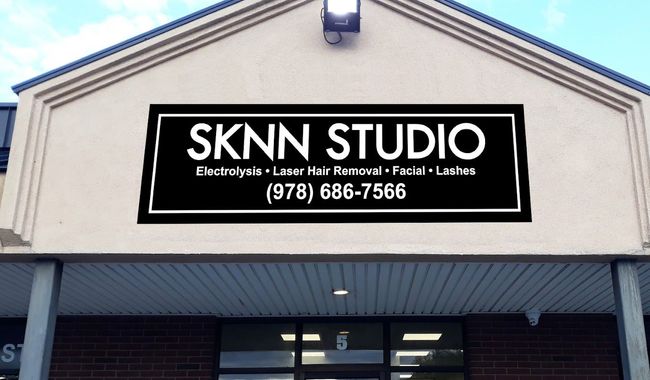 A sign on the side of a building that says sknn studio