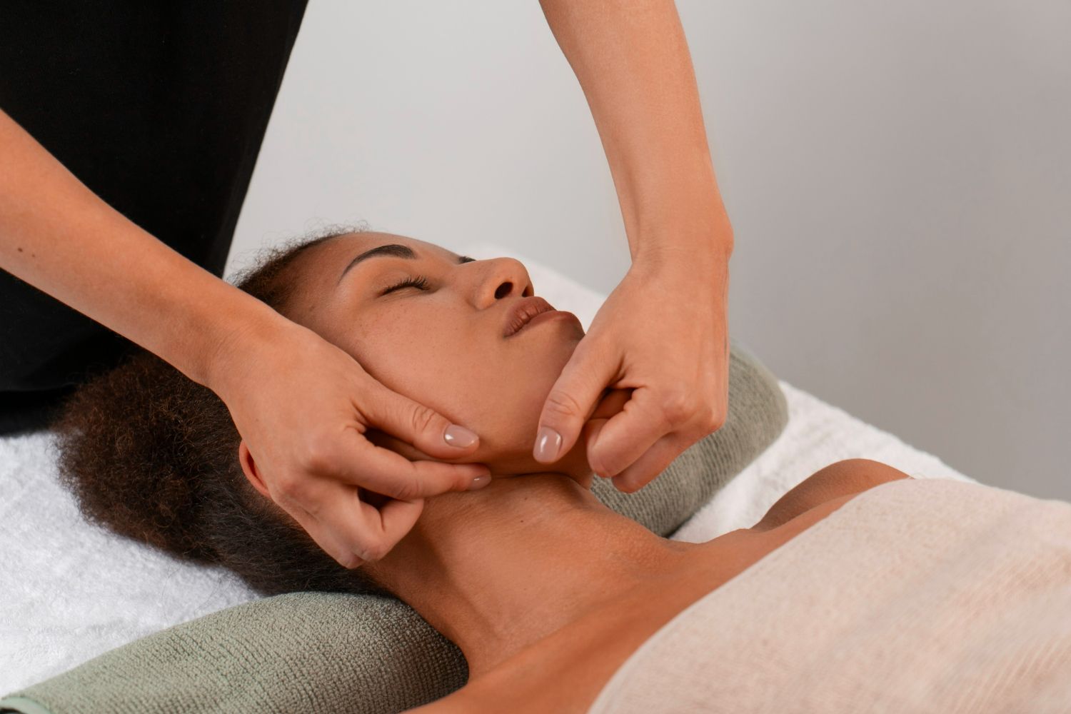 A woman is getting a face massage at a spa.