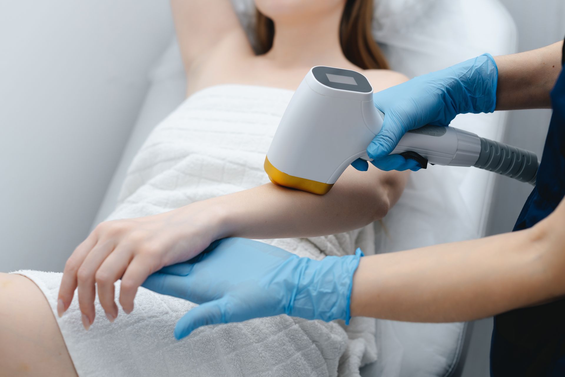 A woman is getting a laser hair removal treatment on her arm.