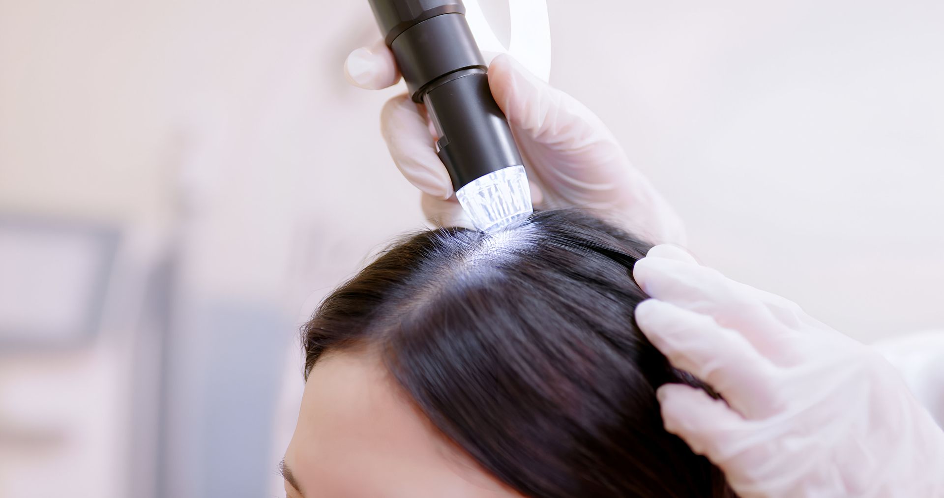 A woman is getting her hair examined by a doctor with a microscope.